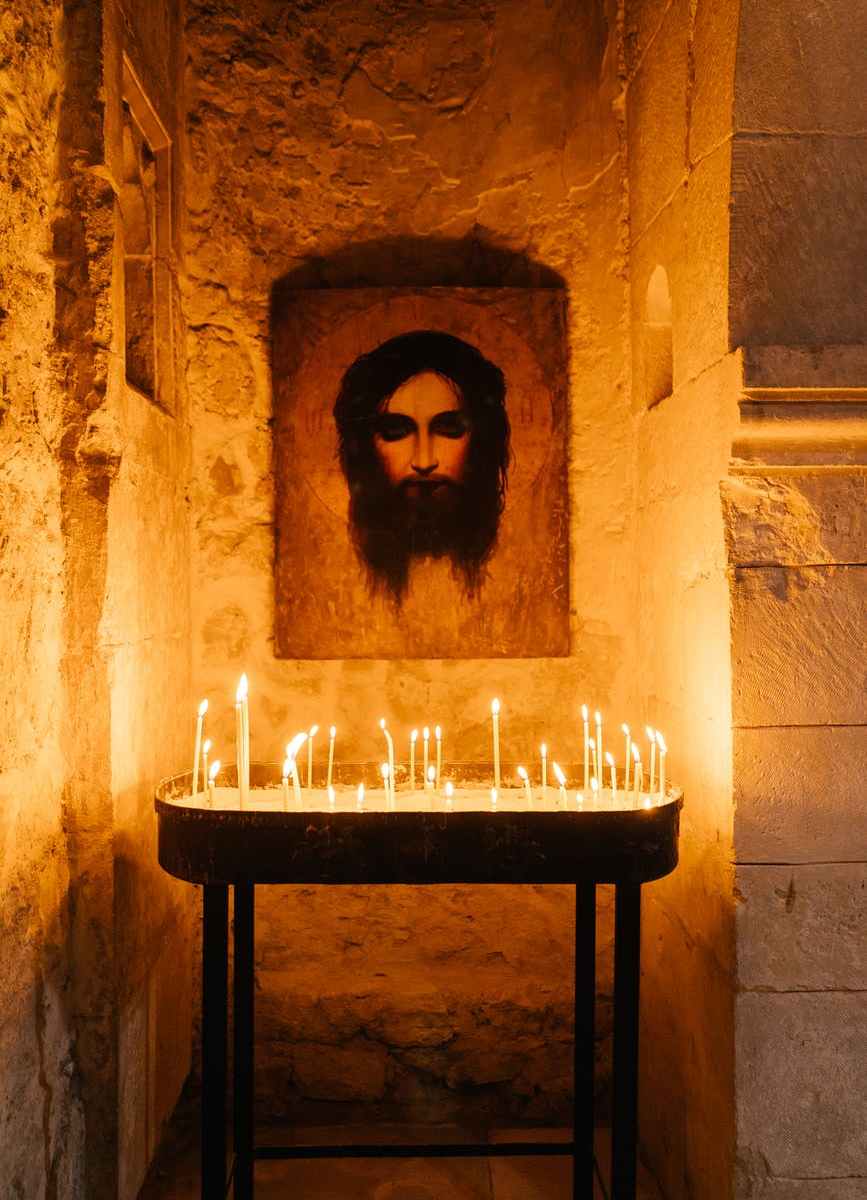 painting of jesus christ and lighted candles on a table