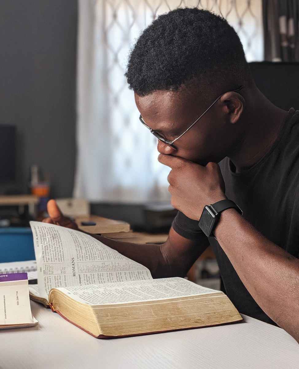 man wearing black crew neck shirt reading book