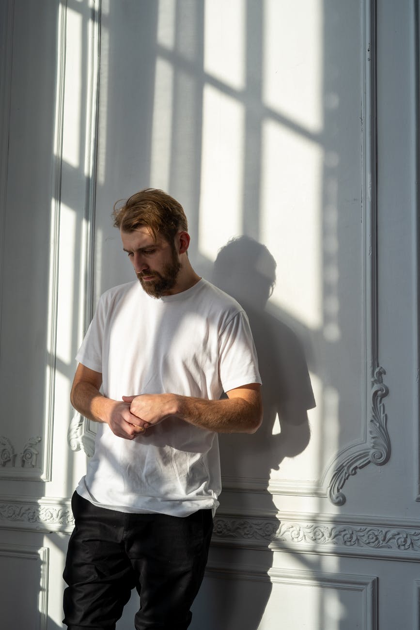 man in white crew neck t shirt standing beside window